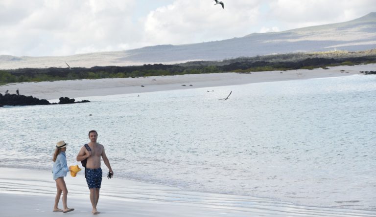 Cerro Brujo - San Cristobal in Galapagos Islands, tourist walking in the beach and watching the sea