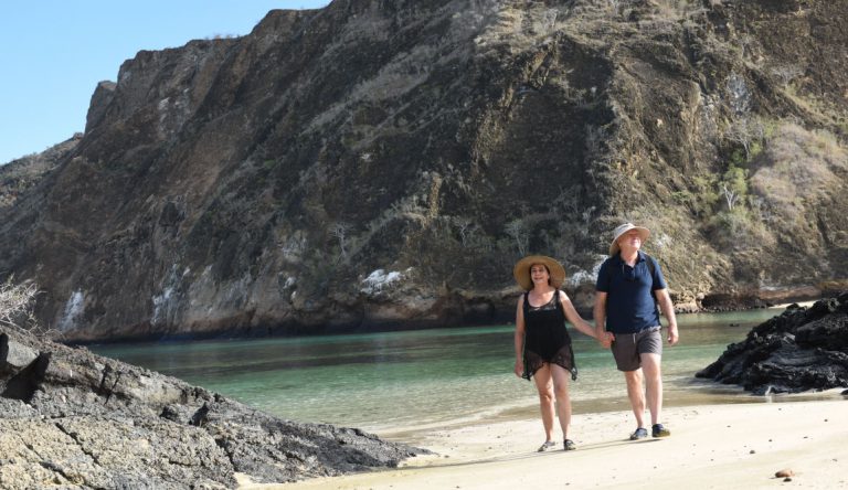 Cerro Brujo - San Cristobal in Galapagos Islands, tourist walking in the beach and watching the sea