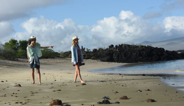 Cerro Brujo - San Cristobal in Galapagos Islands, tourist walking in the beach and watching the sea