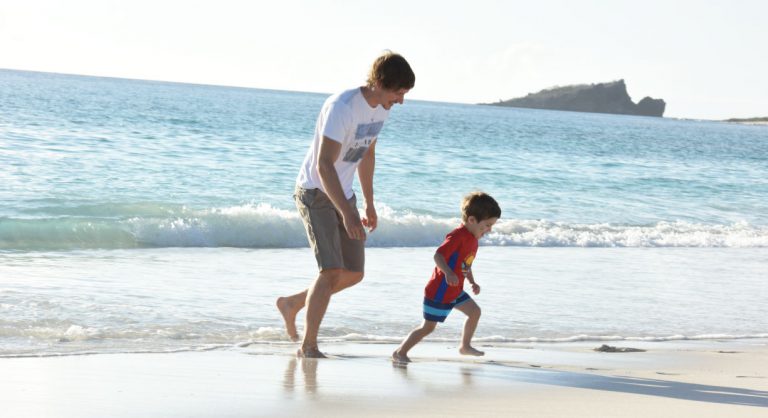 Gardner Bay - Española in the Galapagos view of the white sand beach with tourist play with child