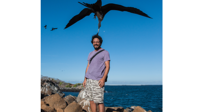 North Seymour in Galapagos Islands with tourist playing with a frigate