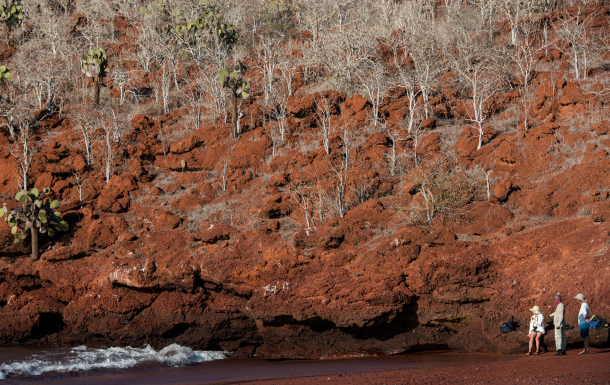 Rabida in Galapagos Islands, view of the red hill and sand with tourist looking around